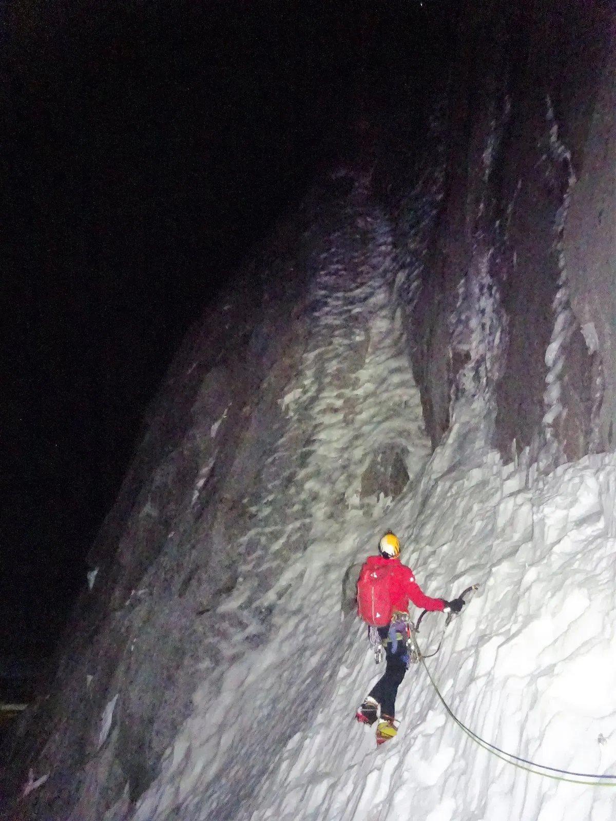Alastair starting up a steep ice pitch in a red jacket