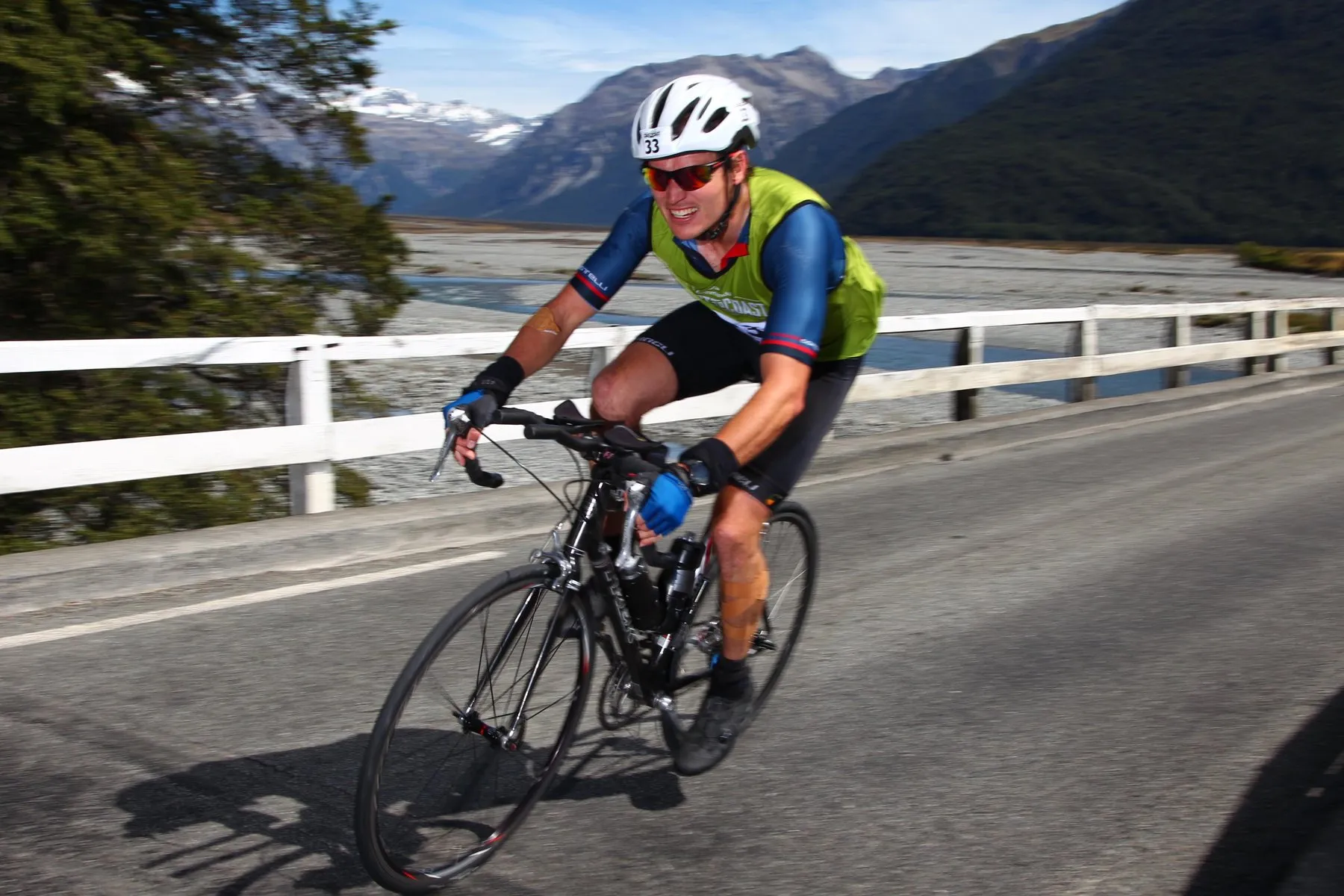 Alastair riding a road bike across a bridge in a race