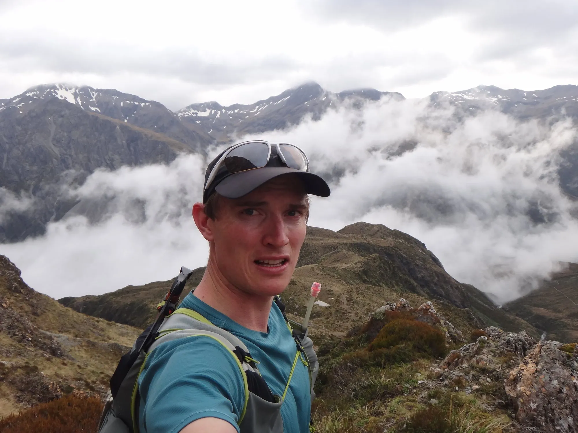 Alastair in a running vest with a soft flask, cloud filling the valleys below